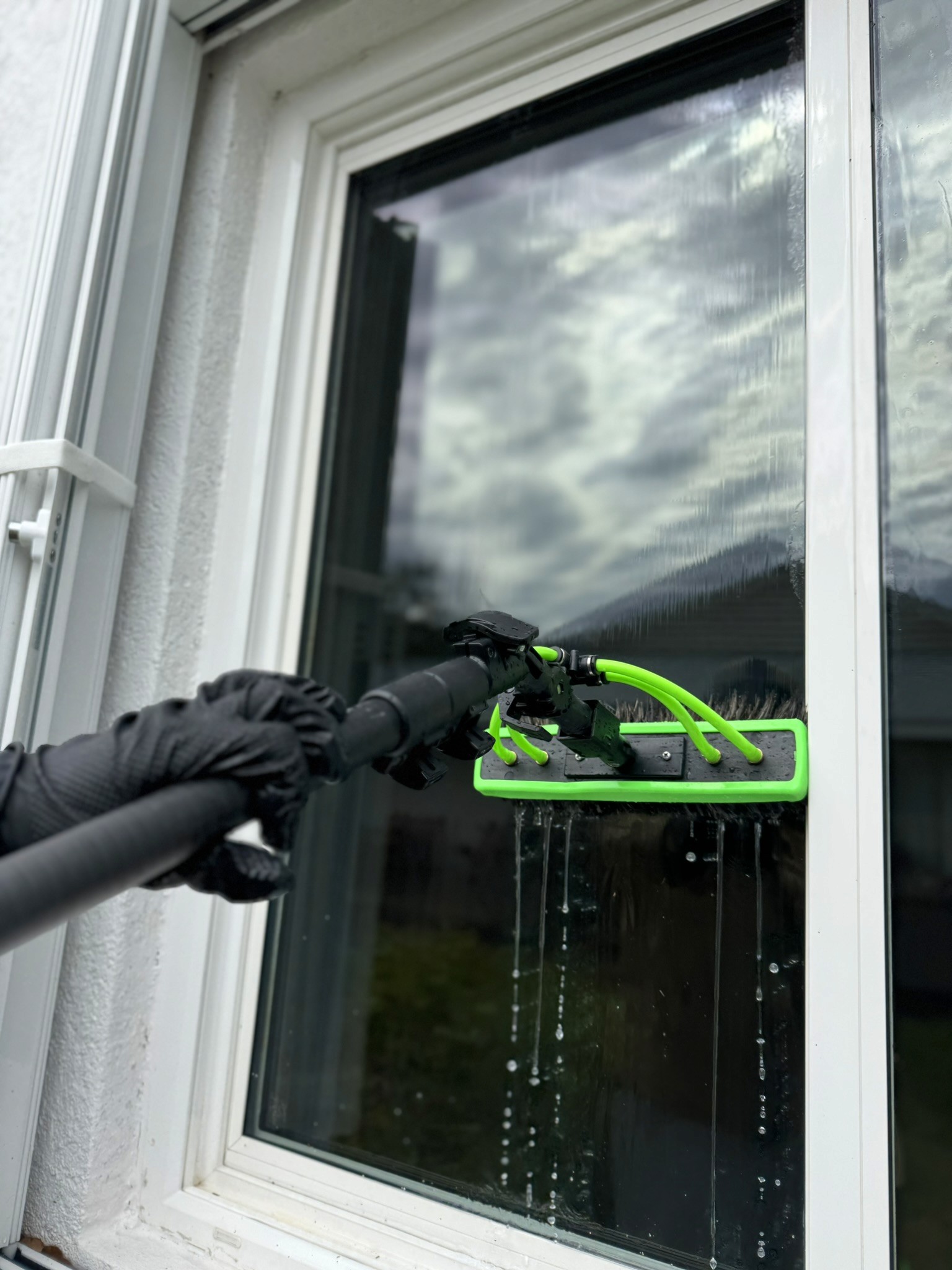 Backwater cleaning a residential window with a water-fed brush